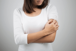 Woman Scratching Her Arm — New Bern, NC — East Carolina Dermatology and Skin Surgery PLLC
